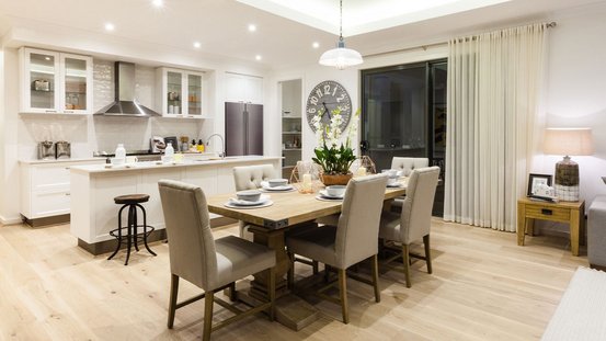 Der Raum ist hell erleuchtet und zeigt eine stilvolle Kombination aus Holz- und weißen Möbeln, ergänzt durch Pflanzen und Dekoration.