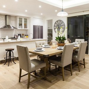 Ein eleganter Essbereich mit einem großen Holztisch, umgeben von bequemen Stühlen und einer modernen Kücheneinrichtung.